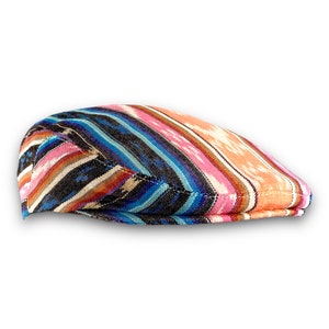 Peut inclure: Une casquette plate à motif coloré avec un design rayé bleu, rose, orange et noir.