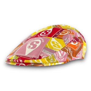 May include: A yellow, red, and orange patterned cap with the words "Strawberry Chew", "Cherry Chew", and "Orange Chew" printed on it.