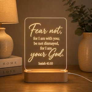 May include: A rectangular acrylic light panel with a wooden base, featuring the illuminated text: Fear not, for I am with you; be not dismayed, for I am your God. Isaiah 41:10. The warm glow highlights the script lettering against the clear surface.