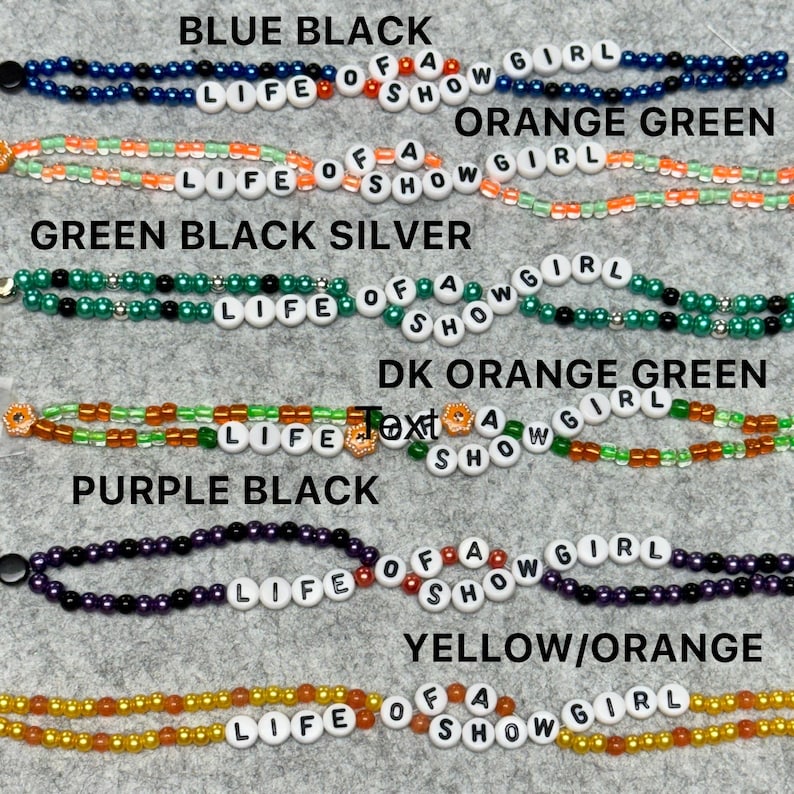 May include: A collection of beaded bracelets in various color combinations, including blue and black, orange and green, and purple and black. Each bracelet spells out "LIFE OF A SHOW GIRL" with white letter beads.