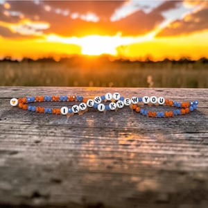 May include: Two beaded bracelets featuring alternating orange and blue faceted beads. One bracelet displays the white letter beads spelling I KNEW IT, while the other displays I KNEW YOU. A small white bead with an orange heart is at the end.