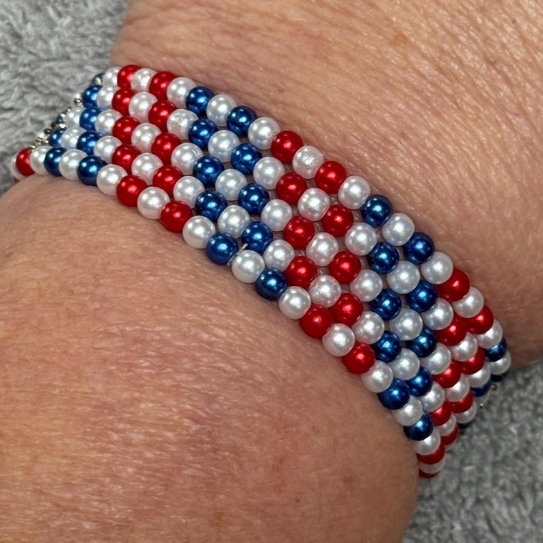 A beaded bracelet made up of 5 rows featuring alternating rows of red, white, and blue beads. The bracelet is made of small, round beads, creating a patriotic color scheme. The bracelet is designed to be worn on the wrist.