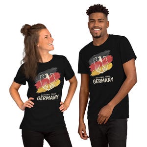 May include: Black t-shirts featuring the German national team logo. The design includes the German flag colors: black, red, and yellow, with a stylized eagle emblem. The text "NATIONAL TEAM GERMANY" is printed below the graphic.