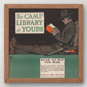 Peut inclure: Affiche vintage encadrée représentant un soldat lisant un livre. Le texte de l'affiche indique "The Camp Library is Yours" et "Read to Win the War". La palette de couleurs comprend des tons de marron, de vert et de noir.