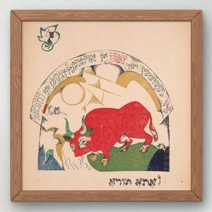 May include: A framed print featuring a red bull with green horns and hooves, set against a backdrop of geometric shapes and text. The artwork has a vintage aesthetic, with a wooden frame and a cream-colored background.