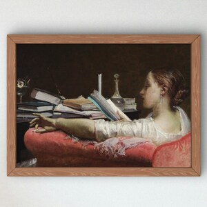 Peut inclure: Une impression d'art encadrée représentant une personne vêtue d'un vêtement blanc allongée sur une chaise longue en velours rouge en train de lire un livre. La scène montre un fond sombre avec une table portant des livres empilés, une carafe en verre.
