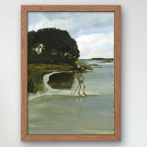 May include: A framed wall art print featuring a painting of a human skeleton walking along a riverbank. The scene includes dark green trees, a light-colored sandy shore, and a calm river under a cloudy sky. The frame is made of light brown wood.