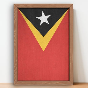 Peut inclure: Une toile encadrée représentant le drapeau du Timor oriental. Le drapeau est rouge avec un triangle noir contenant une étoile blanche au centre. Le triangle est bordé de lignes jaunes.