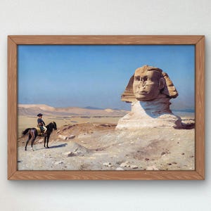 Peut inclure: Une peinture représentant le Grand Sphinx de Gizeh dans le désert. Une personne à cheval est en train de monter à cheval au premier plan.