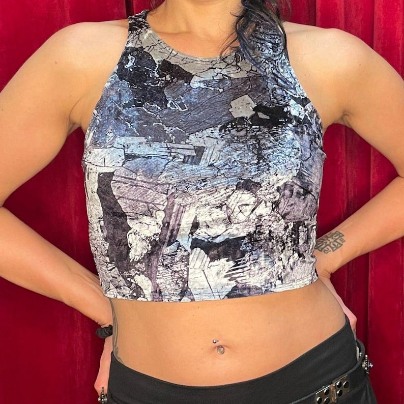 May include: A cropped tank top with a black and white abstract print. The top is made of a soft, velvety fabric.