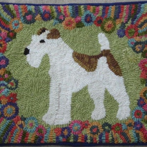 May include: Hand-hooked rug featuring a white and brown dog on a green background. The dog is surrounded by a border of colorful flowers and rainbow-striped patterns. The rug has a dark blue border.