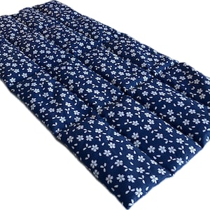 Peut inclure: Un coussin chauffant rectangulaire à motif floral bleu et blanc avec plusieurs compartiments. Le coussin est matelassé.
