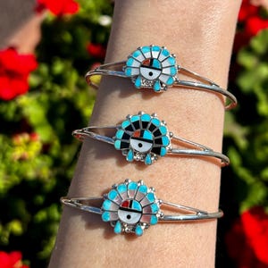 Op de afbeelding: Drie zilveren armbanden met turquoise en rode inleg. Elke armband heeft een ander ontwerp van een Indiaans symbool.