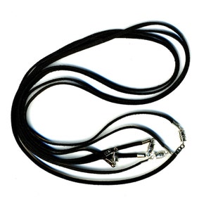 May include: A black suede cord necklace with silver clasps. The cord is layered and tied together with the clasps.