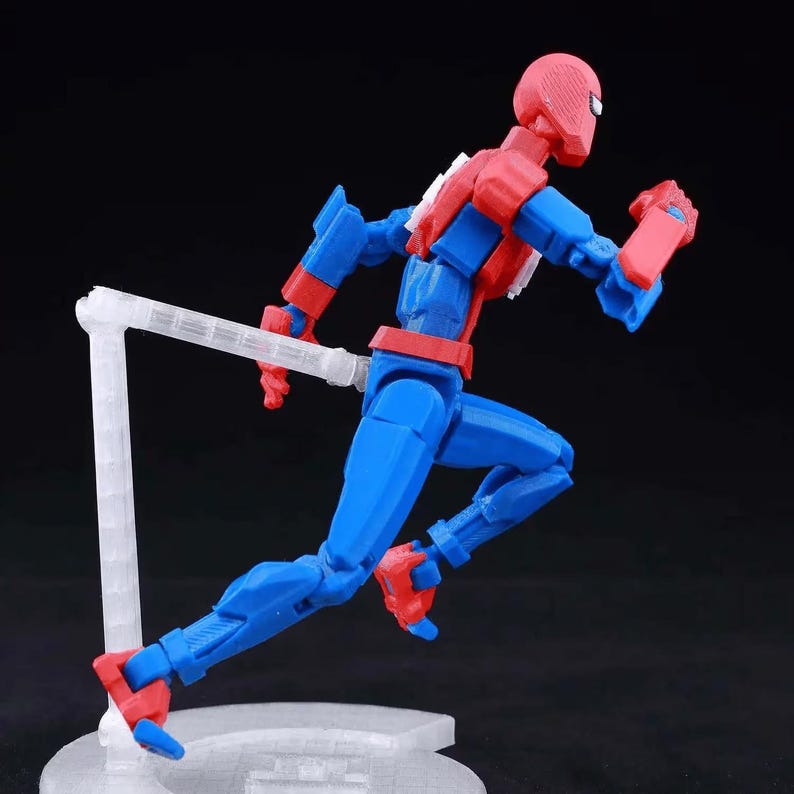 May include: A red and blue articulated action figure in a running pose, supported by a clear plastic stand. The figure features a textured mask, segmented limbs, and a white emblem on the chest, captured from a side profile against a black background.