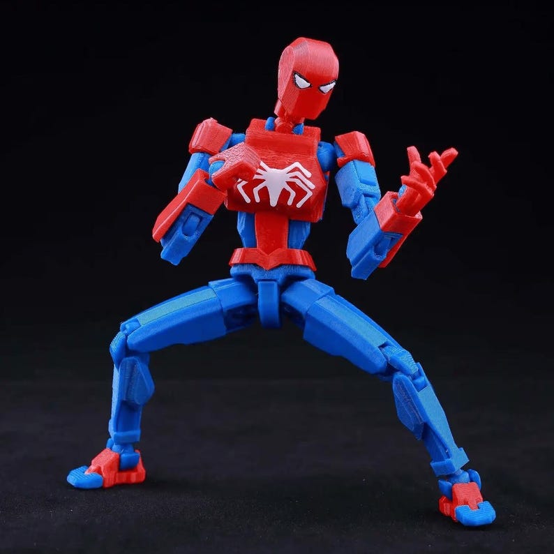 May include: A posable action figure featuring a red and blue color scheme with a white spider emblem on the chest. The figure has a geometric, segmented design with visible joints at the shoulders, elbows, hips, and knees, posed in a dynamic stance.