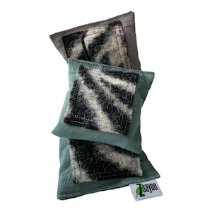 Peut inclure: Deux housses de coussin en tissu vert avec des inserts en tissu à motifs noir et blanc. Les housses de coussin ont un logo de feuille verte avec le texte "Zayne" dans le coin inférieur droit.