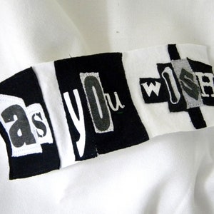 May include: Black and white fabric banner with the words "as you wish" in a patchwork style.