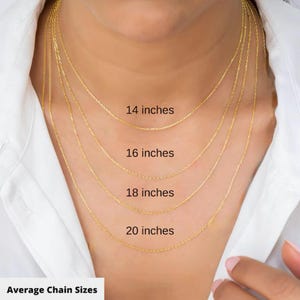 May include: A close-up of a person wearing four gold-colored necklaces of varying lengths: 14, 16, 18, and 20 inches. The text "Average Chain Sizes" is at the bottom of the image. The person is wearing a white shirt.