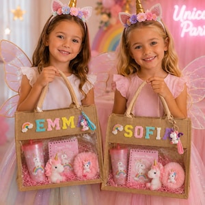 Puede incluir: Dos bolsas rectangulares de yute con paneles frontales transparentes, personalizadas con letras de fieltro de colores que forman EMMA o SOFIA. Cada bolsa contiene un vaso de unicornio rosa, un cuaderno pequeño, un unicornio de peluche y un pompón.