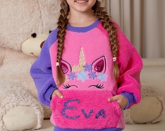 May include: A pink and purple fleece sweatshirt with a unicorn design and the name "Eva" embroidered on the front pocket.