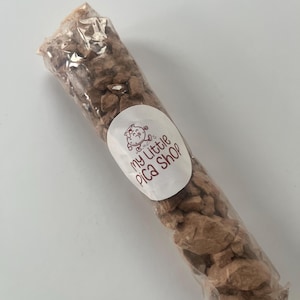 May include: A clear plastic tube filled with small, irregular brown clay-like chunks. An oval white sticker is attached to the center of the tube, featuring a cartoon illustration and the text "my little pica shop" in brown lettering.