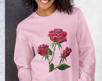 Könnte beinhalten: Ein rosa Sweatshirt mit einem Aufdruck von drei roten Rosen an einem Stiel mit grünen Blättern.