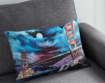 May include: A pillow with a painting of the Golden Gate Bridge at night with a full moon in the sky. The bridge is red and the sky is blue and purple.