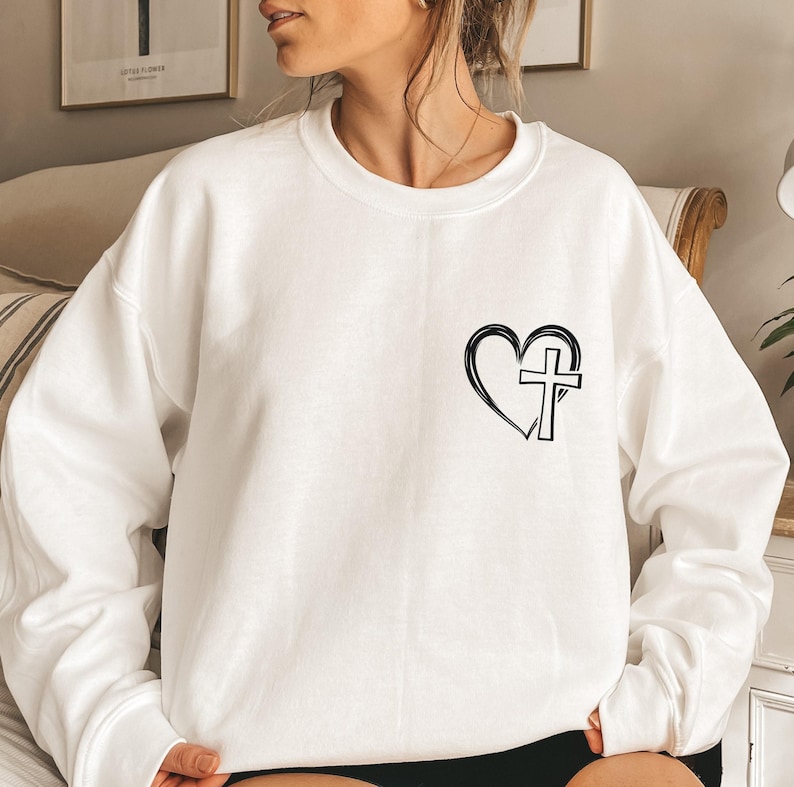 May include: White sweatshirt with a black heart and cross graphic.
