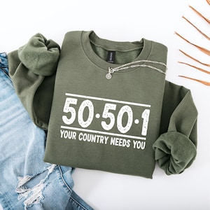 Peut inclure: Un sweat-shirt vert avec le texte "50-50-1 Your Country Needs You" imprimé sur le devant.