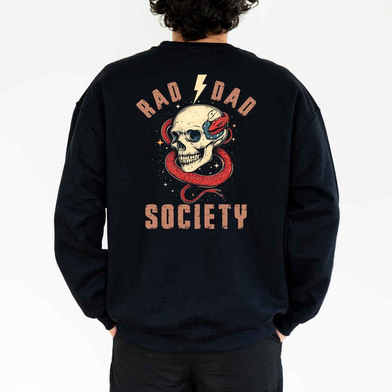 May include: Black sweatshirt with a graphic print of a skull with a snake wrapped around it. The text "Rad Dad Society" is printed in brown letters on the back of the sweatshirt.