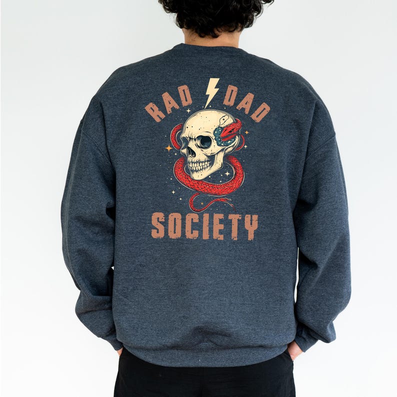 May include: A dark blue sweatshirt with a graphic print of a skull with a snake wrapped around it. The text "Rad Dad Society" is printed below the skull.