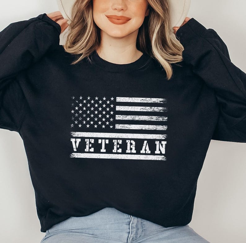 May include: Black sweatshirt with a white distressed American flag and the word "VETERAN" printed on it.