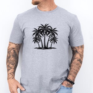 Pode incluir: Uma camiseta cinza com uma silhueta preta de cinco palmeiras na frente.
