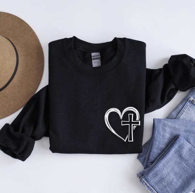 May include: Black sweatshirt with a white heart and cross design. The heart is outlined and the cross is inside the heart.