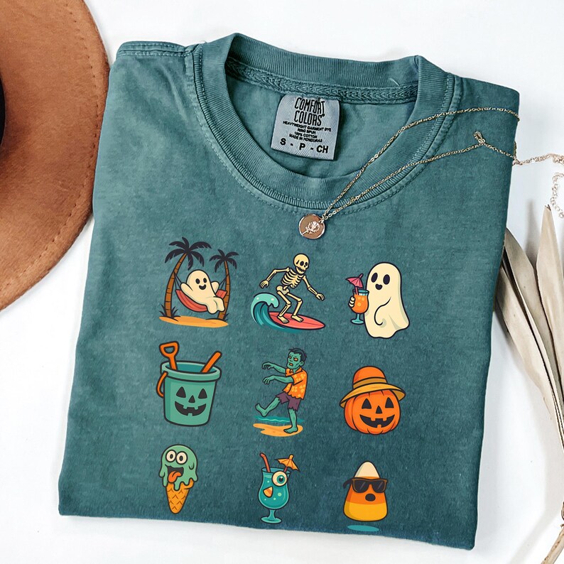 May include: Teal Comfort Colors t-shirt with a variety of Halloween-themed graphics. The graphics include a ghost in a hammock, a skeleton surfing, a ghost with a drink, a jack-o'-lantern bucket, a zombie, a pumpkin with a hat, an ice cream cone, a cocktail, and a candy corn.
