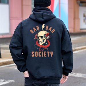 May include: Black hooded sweatshirt with a graphic print of a skull with a snake wrapped around it. The text "Rad Dad Society" is printed on the sweatshirt.