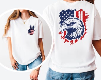 May include: White t-shirt featuring a peace sign with an American flag design on the front and an eagle graphic on the back. The eagle is set against a backdrop of the American flag in red, white, and blue.
