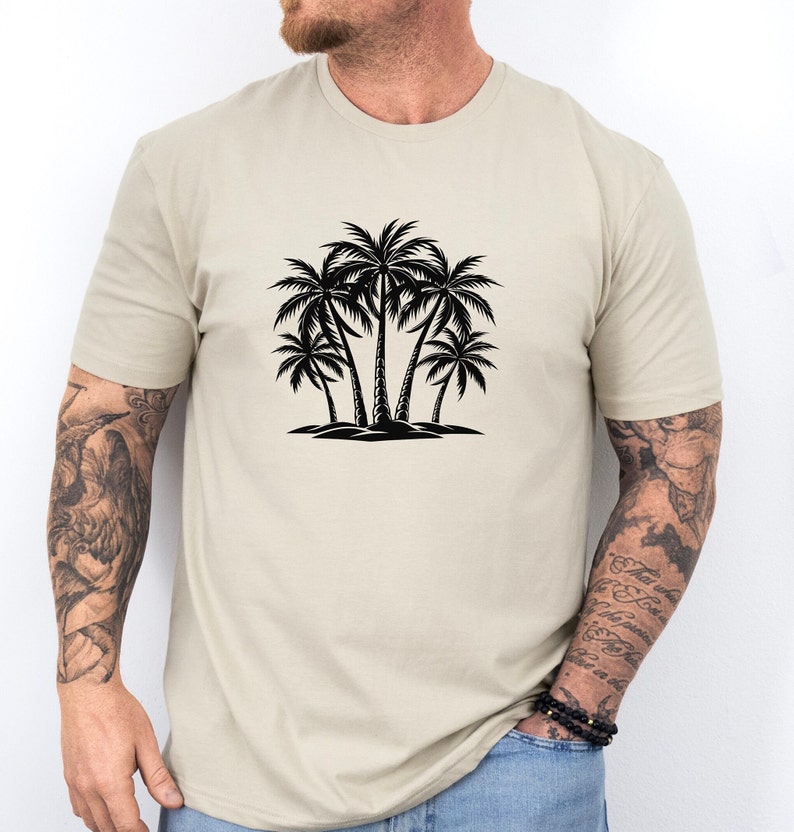 Pode incluir: Uma camiseta bege com uma silhueta preta de palmeiras na frente.