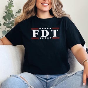 May include: A black t-shirt with a white graphic that says "FDT" with red stars and stripes above and below the text.