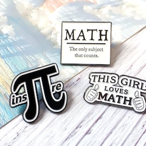 Puede incluir: Tres pines de esmalte con diseños relacionados con las matemáticas. Un pin es un cuadrado blanco con la palabra "MATH" y el texto "The only subject that counts". Otro pin es un símbolo Pi en blanco y negro con la palabra "inspire". El tercer pin dice "THIS GIRL LOVES MATH".
