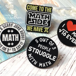 May include: Four enamel pins with math-related phrases. One pin says "I have a scary joke about math but I'm 2² to say it." Another says "Come to the math side, we have π." The third says "I ❤️ √16 Ever Maths." The last says "5 out of 3 people struggle with math."