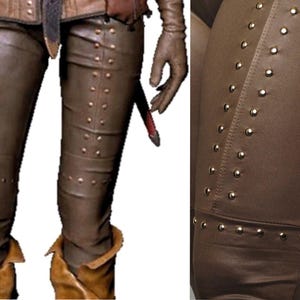 May include: Brown leather pants with gold-toned studs along the seams. The pants have a slim fit and are made of a soft, supple leather.