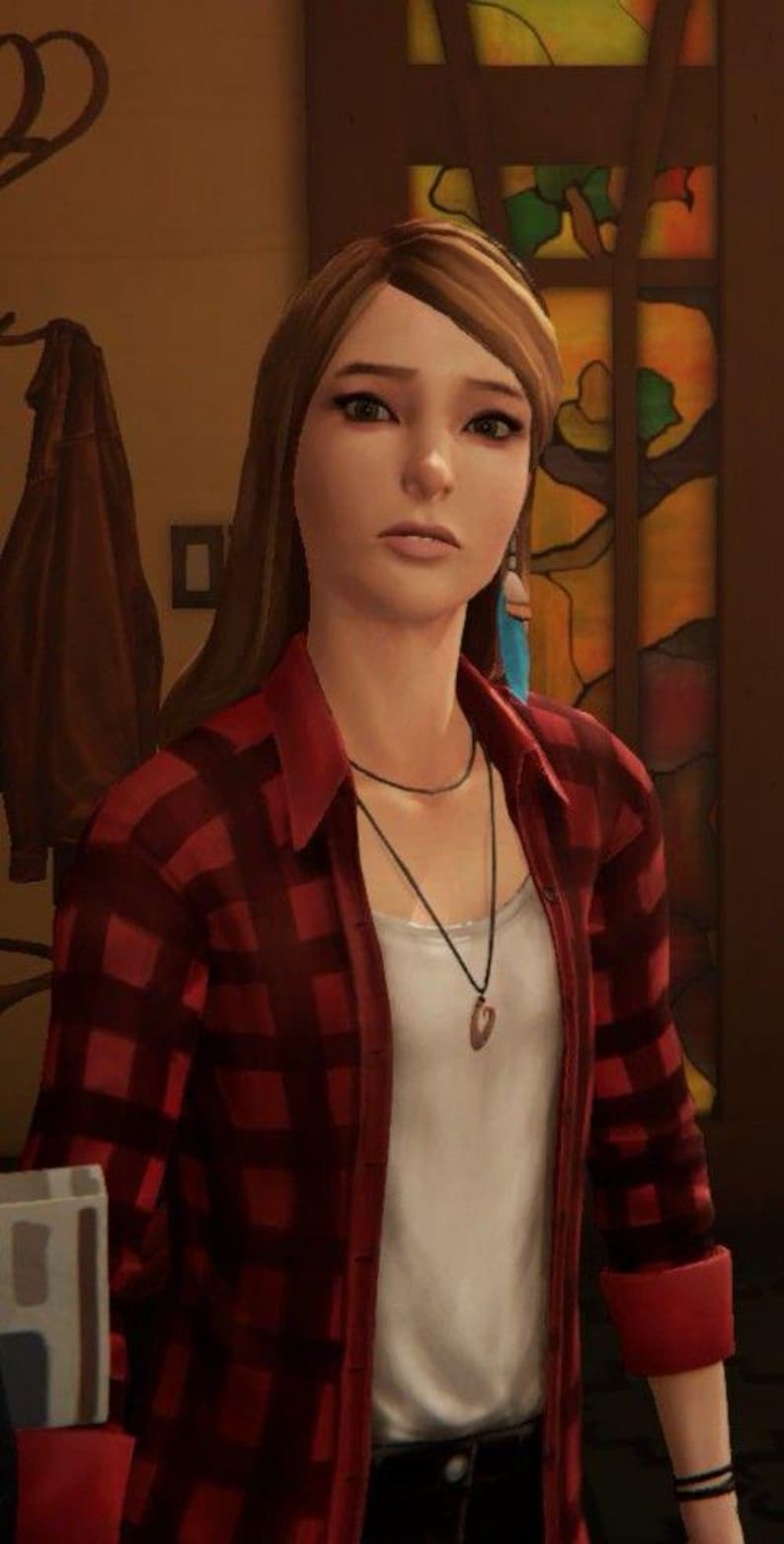 May include: A young woman with long brown hair wearing a red and black plaid shirt over a white t-shirt. She is wearing a black necklace with a pendant and blue feather earrings.
