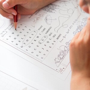 May include: A word search puzzle with the title "On Mr. Tumnus's Table Ward Seale" is being completed with a red pencil. The puzzle includes words like "toast" and "egg". The image also features a drawing of an umbrella.