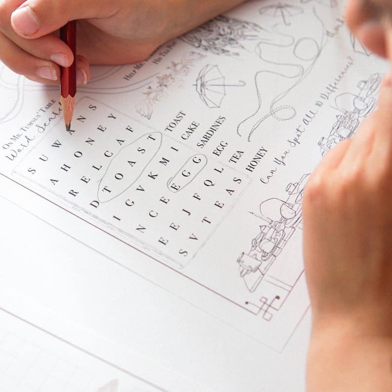 May include: A word search puzzle with the title "On Mr. Tumnus's Table Ward Seale" is being completed with a red pencil. The puzzle includes words like "toast" and "egg". The image also features a drawing of an umbrella.