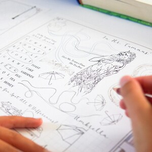 May include: A partially completed activity book page with pencil sketches and handwritten text. The page features a word search, illustrations of umbrellas, and a drawing of a mythical creature. The text includes phrases like "Help Mr. Tumnus Find His Tea Pot" and "Umbrella".