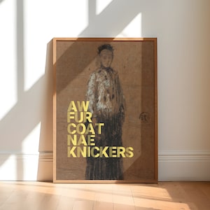 May include: A framed artwork featuring a figure in a coat, with the words "AW FUR COAT NAE KNICKERS" in gold lettering. The artwork is in a wooden frame, leaning against a white wall, with sunlight casting shadows on the wooden floor.