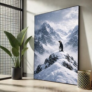 May include: A framed art print featuring a penguin standing on a snow-covered mountain peak. The background shows a majestic mountain range under a cloudy sky. The artwork is displayed in a room with a large window and a potted plant.