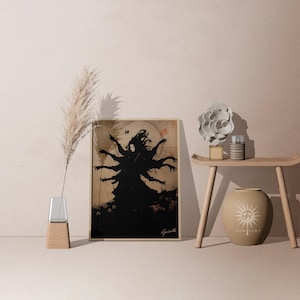 May include: A framed art print featuring a black silhouette of a multi-armed figure against a beige background. The artwork is displayed on a table with decorative items, including a vase with pampas grass and a ceramic vase with a sun design.